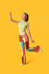 Teenage girl with soap bubbles on yellow background