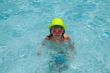 Funny kids face. Child splashing in swimming pool. Swim water sport activity on summer vacation with child.