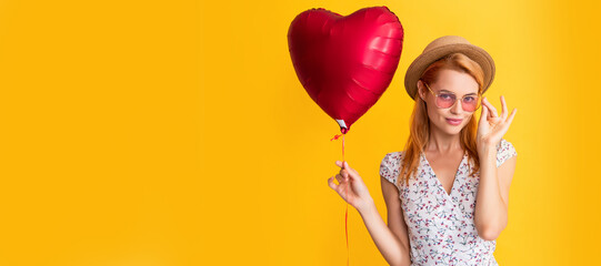 happy girl in eyeglasses hold love heart balloon on yellow background. Woman isolated face...