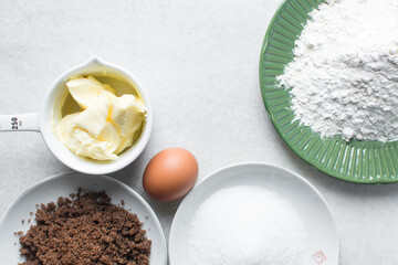 mise en place of ingredients for making brownies, top view of sugar, eggs, butter, flour cocoa powder on a marble table, process of making brownies