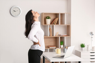 Beautiful young businesswoman suffering from back pain at office