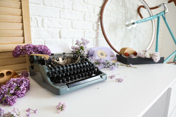 Vintage typewriter with lilac flowers on table in author's office, closeup