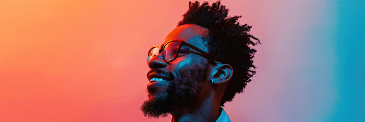 A close-up photo of a smiling man with glasses, looking up towards the right. He is standing against a vibrant red and blue gradient background