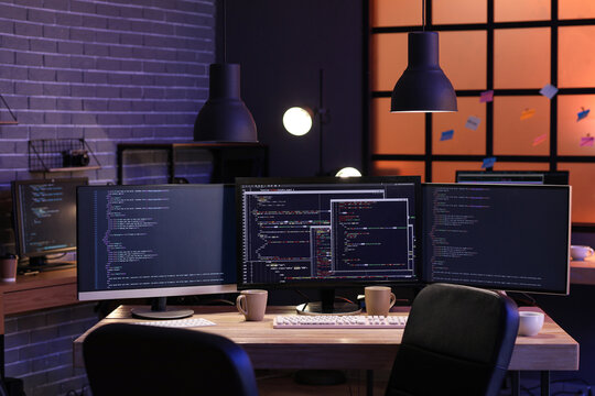 Programmer's workplace with computer monitors in office at night