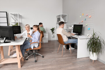 Team of programmers working at tables in office