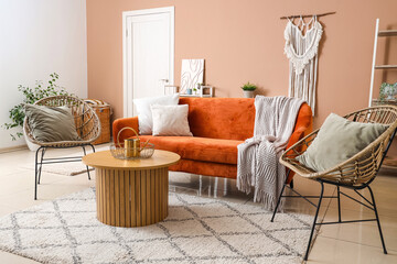 Interior of stylish living room with brown sofa, chairs and coffee table near beige wall