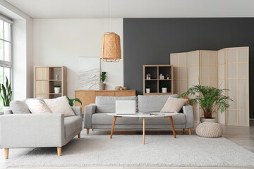 Interior of stylish living room with grey sofas and laptop on table