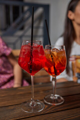 Two friends lifting cocktails in a lively bar scene, expressing joy and celebration