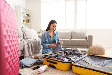 Female Asian traveler putting sunglasses into organizer at home