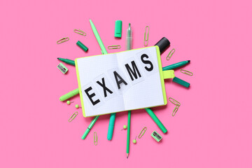 Composition with word EXAMS, notebook and stationery on pink background