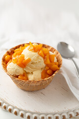 Vanilla Ice Cream in a Waffle Bowl Topped with Fresh Peaches against a White Background