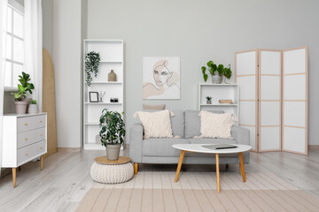 Light living room with folding screen, comfortable sofa, coffee table and chest of drawers