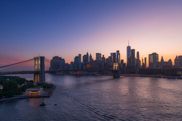 Fototapeta premium Brooklyn Bridge and New York skyline across the East River under an intense sunset.