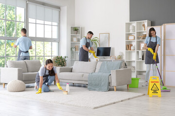 Group of young janitors cleaning in room