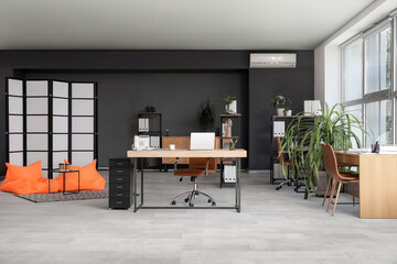 Interior of modern office with desks, beanbags and plants