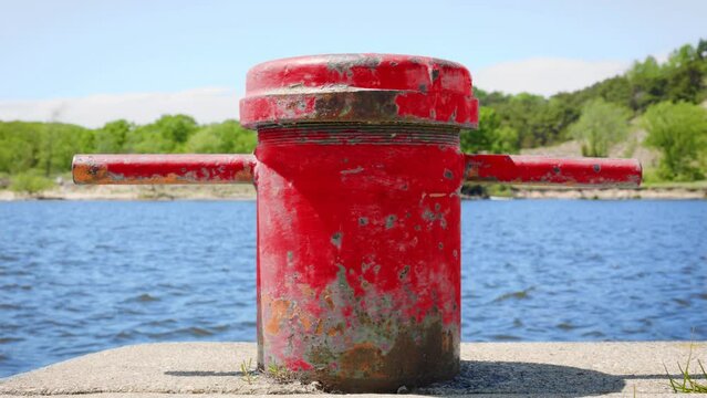 Chipped red metal boat cleat on edge of marina