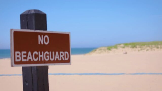 Warning sign no lifeguard on sand dune beach