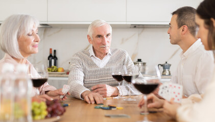 Senior man and woman play card game poker during friendly gatherings at home with middle-aged...