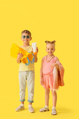Cute little children with sunscreen cream and flippers on yellow background