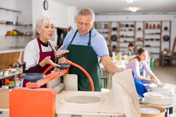 Obraz premium elderly potter passes on experience of hand-making products from fresh clay