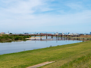 大和川を渡る近鉄道明寺線の電車と河川敷の公園