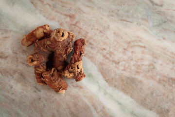 A pile of Dry Organic Kulanjan (Alpinia galanga) roots, on a marble background. Top view