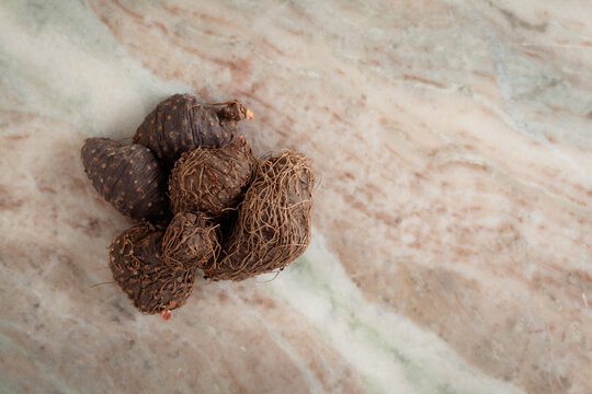 A pile of Dry Organic Varahikanda (Dioscorea bulbifera) fruits, on a marble background. Top view