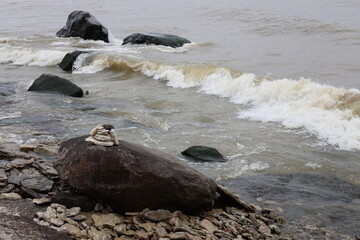 Fototapeta premium piled stone marker on a rock at lake shore