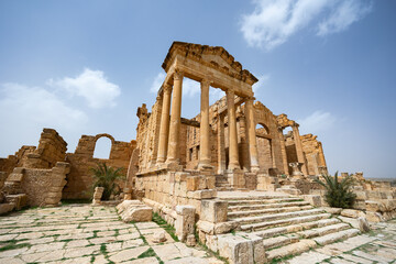 Fototapeta premium Well-preserved golden hued stone ruins of Capitoline Temples standing majestically in antique Roman forum of Sbeitla on sunny spring day, Tunisia