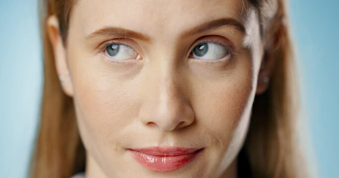Woman, face and annoyed with rolling eyes in studio with closeup, bored and drama for choice by blue background. Girl, person and model with attitude, doubt or raised eyebrow in portrait for decision