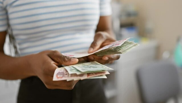 African woman with braids counting dirhams in an office setting implies business and finance activities
