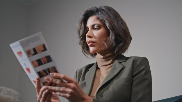 Young woman reading brochure in beauty clinic closeup. Beautiful businesswoman