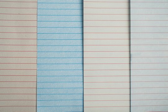 Blue lined paper is surrounded by white lined paper, creating a simple yet visually appealing contrast. The image evokes a sense of individuality and standing out from the crowd
