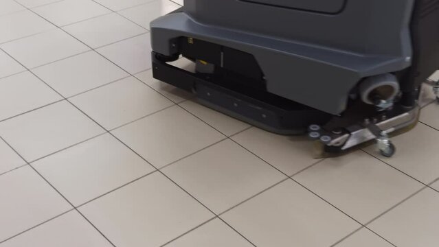 Industrial floor scrubber cleaning tile floor in real time, displaying professional cleaning equipment for maintenance process