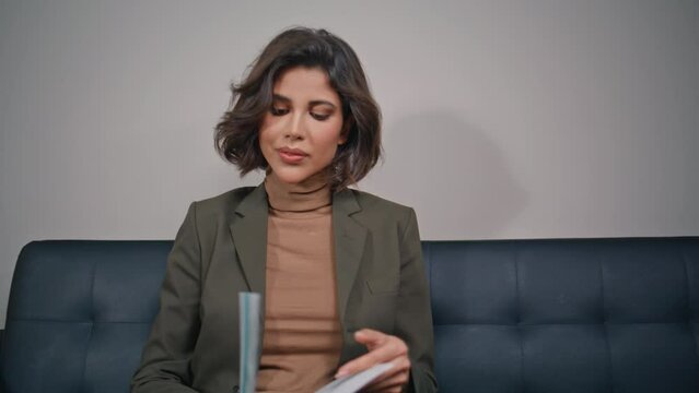 Elegant lady reading information in brochure sitting modern couch closeup. 