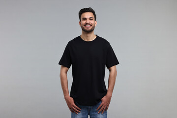 Smiling man in black t-shirt on grey background