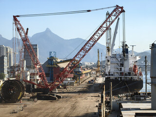 A huge cargo crane loads a ship at the port