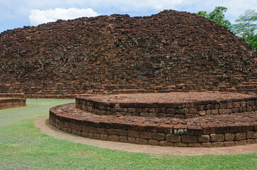 Wonderful ancient laterite block base with khao klang ni in green lawn in world heritage Si Thep...