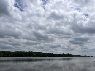 Forest lake on a quiet summer morning, clouds over mountain peaks