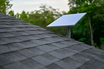 Starlink satellite dish with a wall mount on a shingle roof. Shot on Nikon z5 with 50mm f1.8 lens