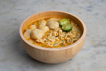 instant noodles with meatballs and lime served in a wooden bowl