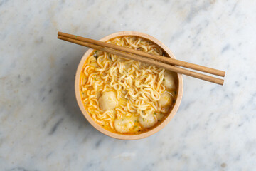 instant noodle with meatballs served in a wooden bowl and chopsticks on top, top view