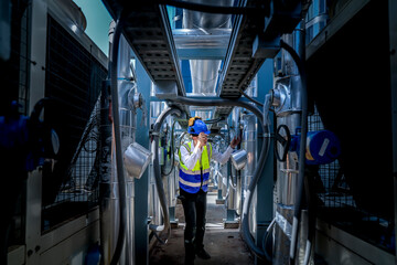 An industrial worker in high-visibility gear and a blue helmet meticulously examines the intricate...