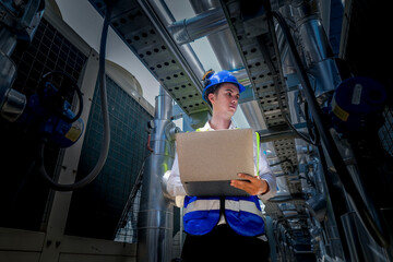 An industrial worker in high-visibility gear and a blue helmet meticulously examines the intricate...