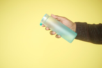 Closeup of hand holding reusable water bottle, promoting ecofriendly lifestyle and hydration