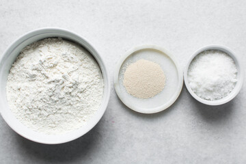 Overhead view of mise en place of ingredients for making nigerian puff-puff, flatlay of flour yeast sugar for puff-puff on a marble countertop, process of making puff-puff or bofrot