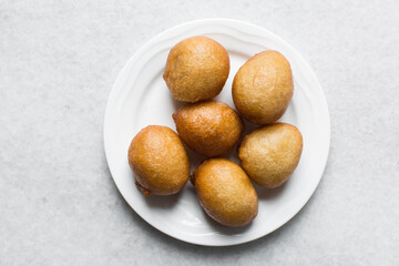 Overhead view of nigerian puff-puff on a white plate, nigerian fried dough balls, flatlay of homemade bofrot on white dish