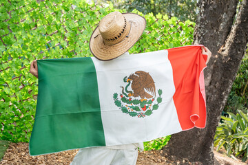 Person with Straw Hat Holding Mexican Flag Outdoors