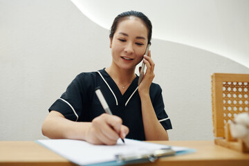 Spa salon receptionist checking price list and filling form on tablet computer