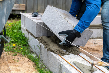 Construction worker laying expanded clay blocks. Foundations of a house, the frame of a new house in the process of construction